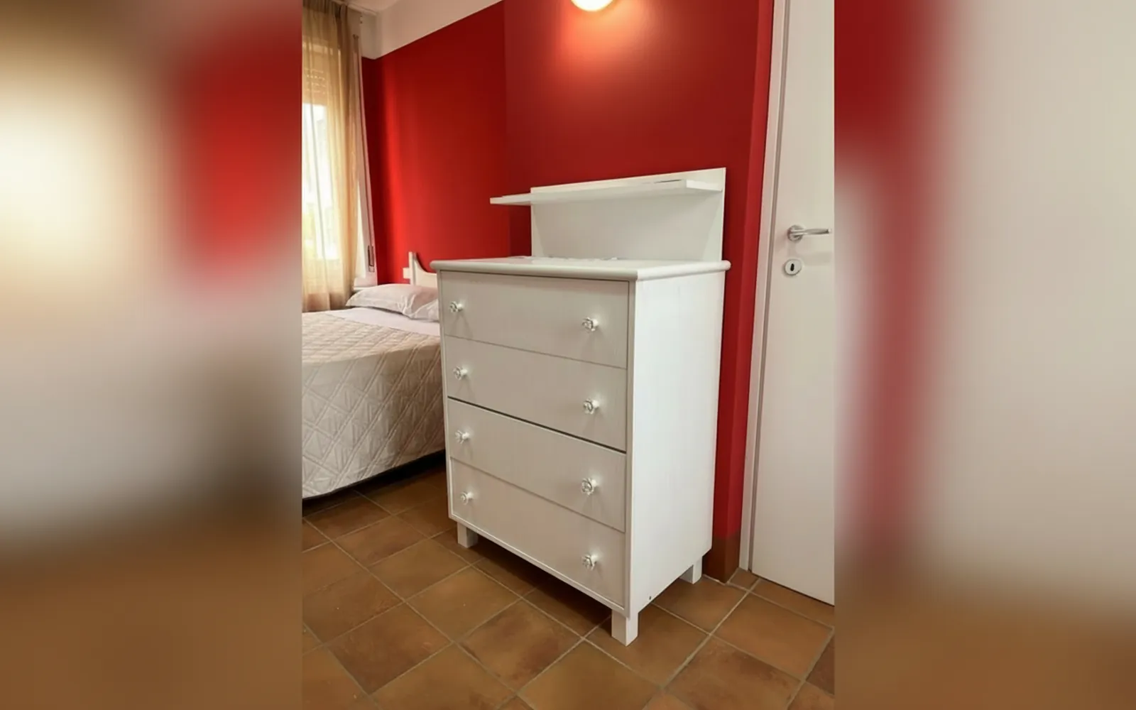 La cassettiera bianca nella camera dalla parete rossa