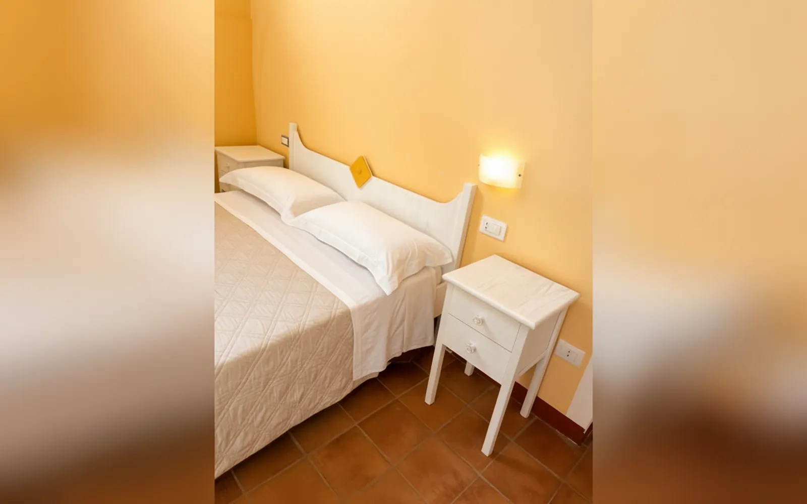 Il letto matrimoniale e il comodino con la lampada a muro